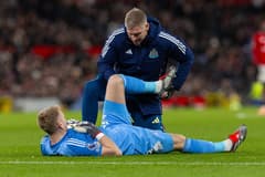 Newcastle goalkeeper Aaron Ramsdale receives treatment for an injury against Manchester United