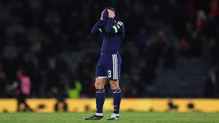Football player standing on the pitch with his hands on his head after a disappointing moment during a football match.