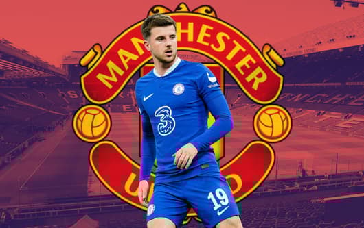 Mason Mount of Chelsea over the Manchester United badge, set against a backdrop of a panorama of Old Trafford in red