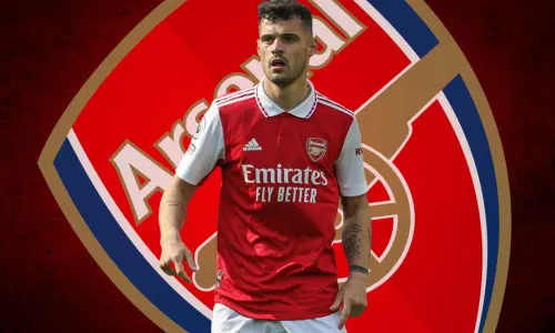 Granit Xhaka in front of the Arsenal badge, on a red and black abstract background