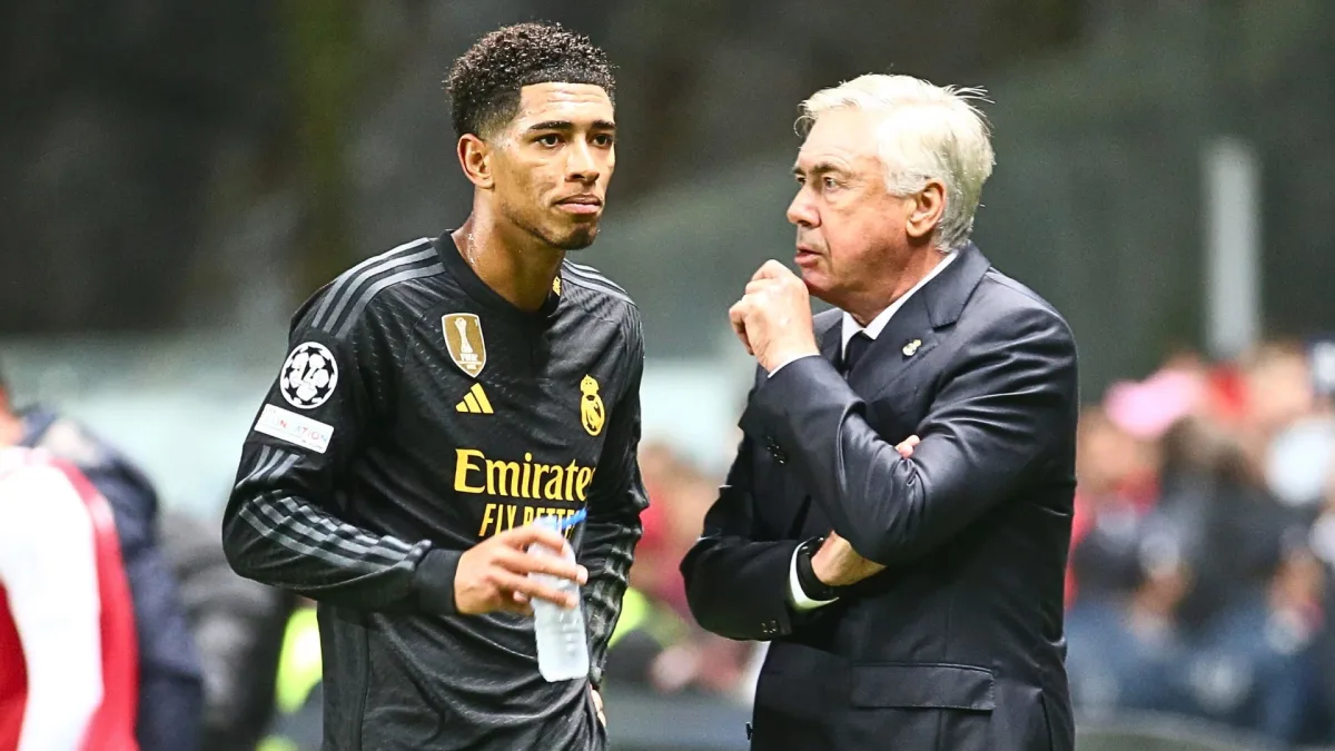  Carlo Ancelotti, the coach of Real Madrid, is giving instructions to Jude Bellingham, a player on the team, during a match.